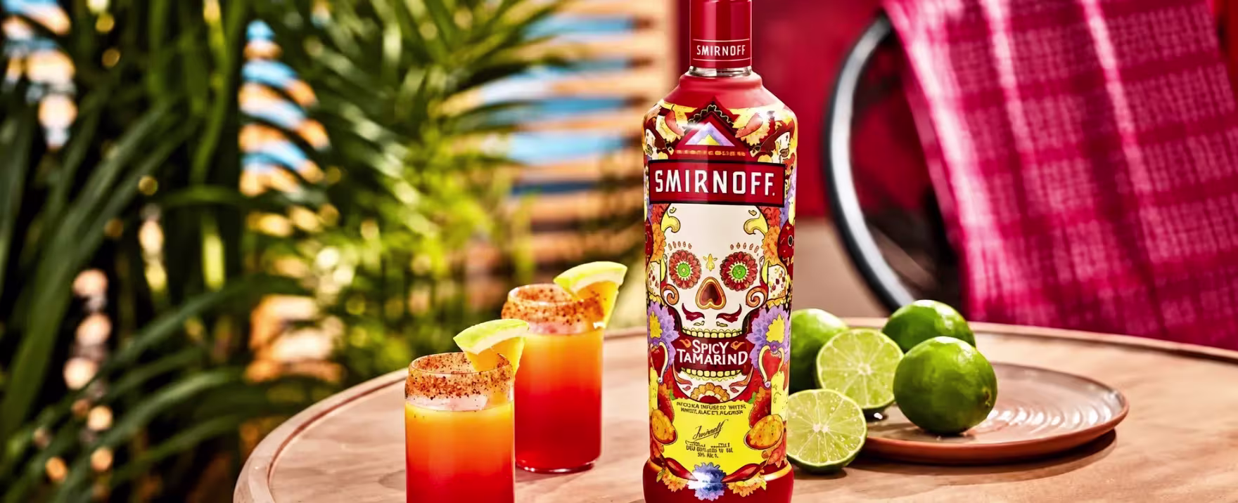 Botella de Smirnoff Spicy Tamarind con dos shots y limones en un ambiente tropical