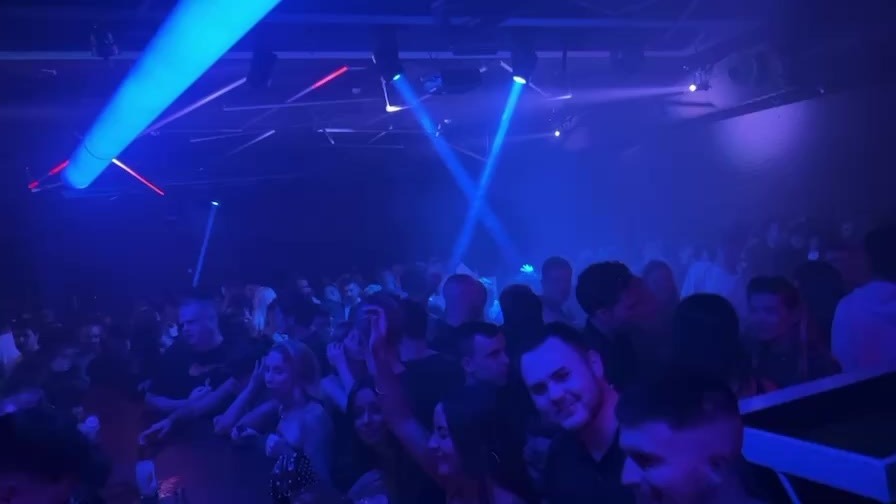 Pista llena en Sala Sonora con luces azules y láseres cruzados sobre el público disfrutando de una noche de música y baile.