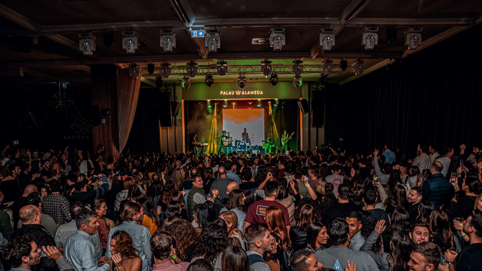 Palau Alameda vibra con un concierto en directo ante una multitud entregada, luces cálidas y un ambiente cargado de energía y emoción.