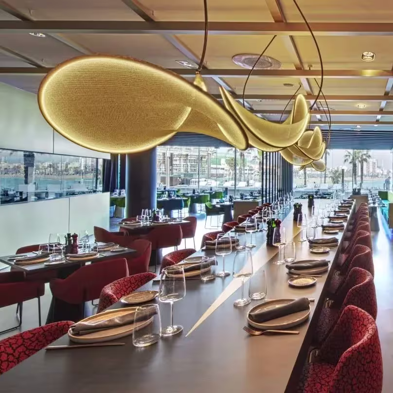 Un espacio moderno y vibrante en Fire, ubicado en el W Hotel, con vistas al puerto y un diseño que combina elegancia y colores cálidos.