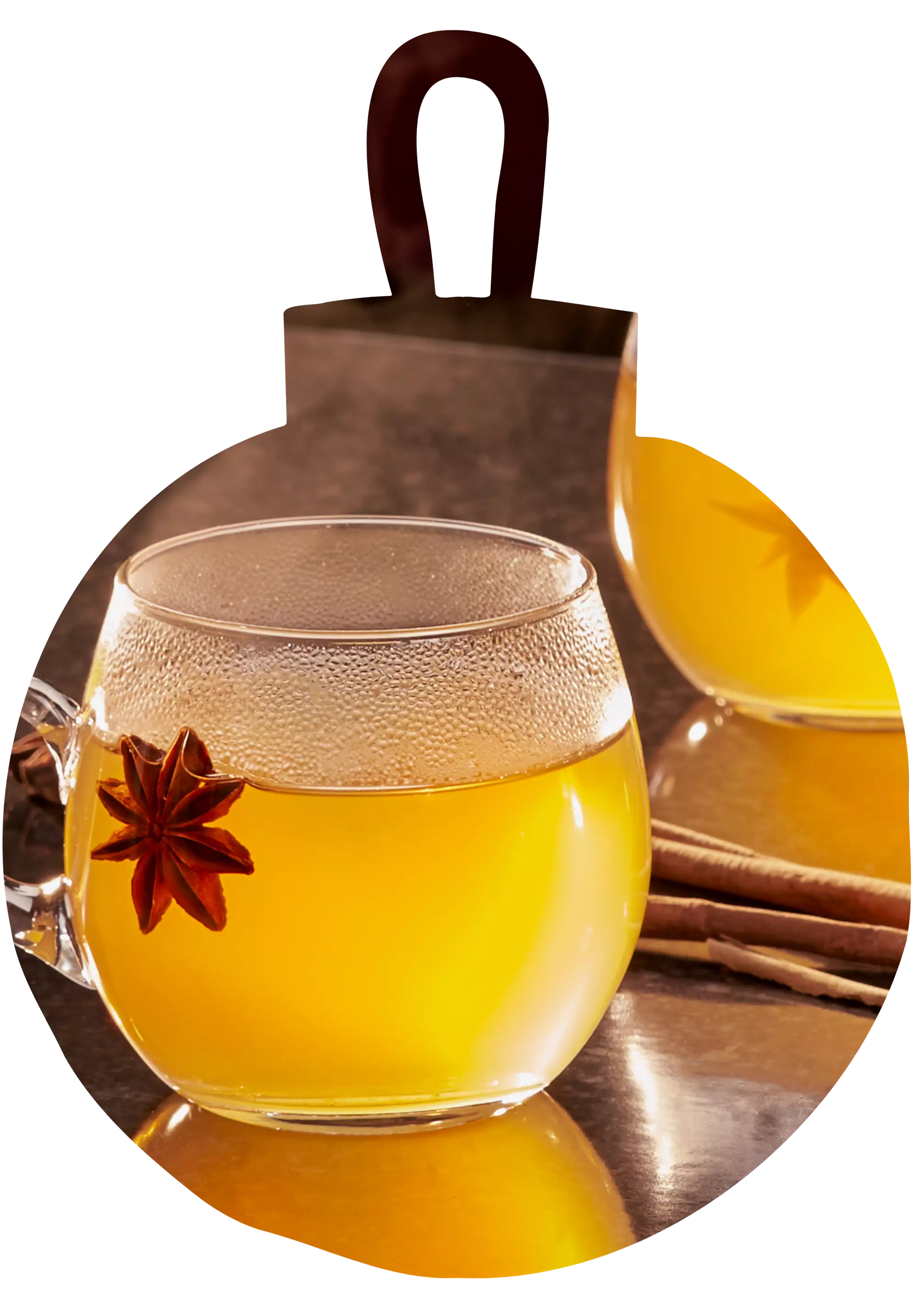A clear glass cup of hot yellow tea garnished with a star anise, with cinnamon sticks and another cup in the background.