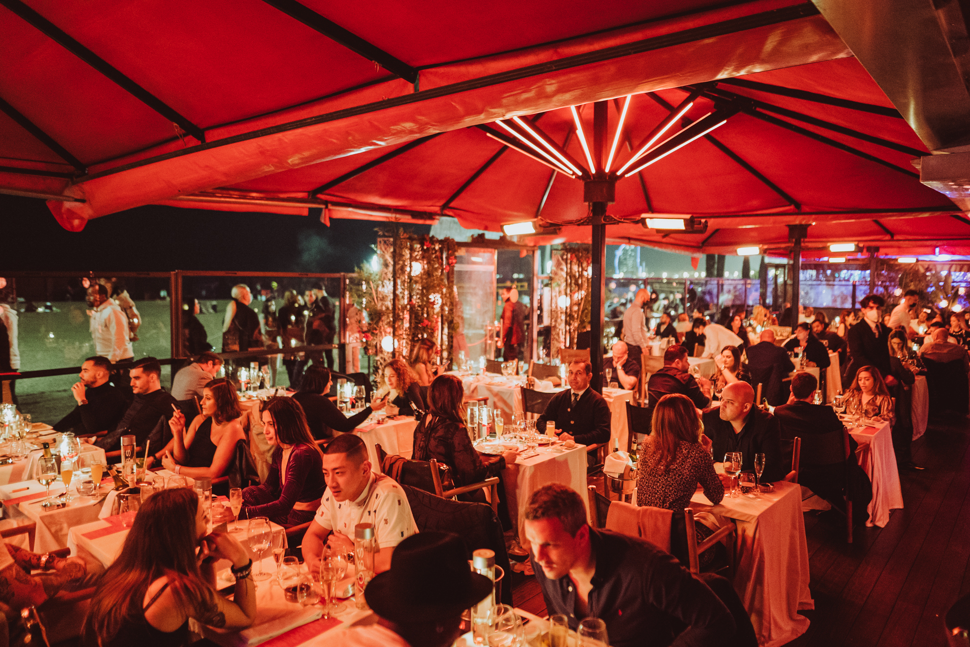 Shoko Barcelona Club, una terraza elegante con mesas iluminadas, rodeada de gente disfrutando de una velada animada bajo una iluminación cálida.