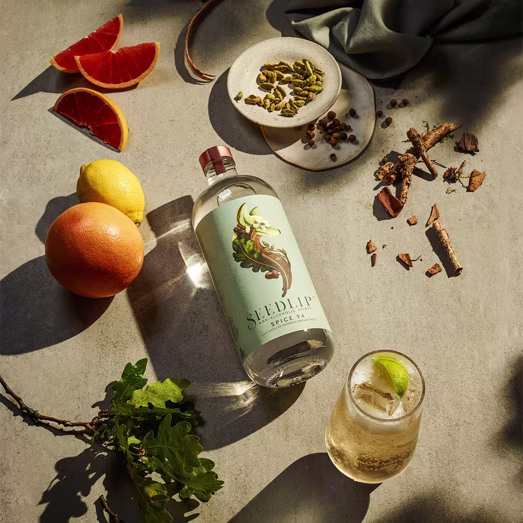 Seedlip Spice 94 Alcohol Free Spirit Bottle on a table with a mocktail, pears and other garnish