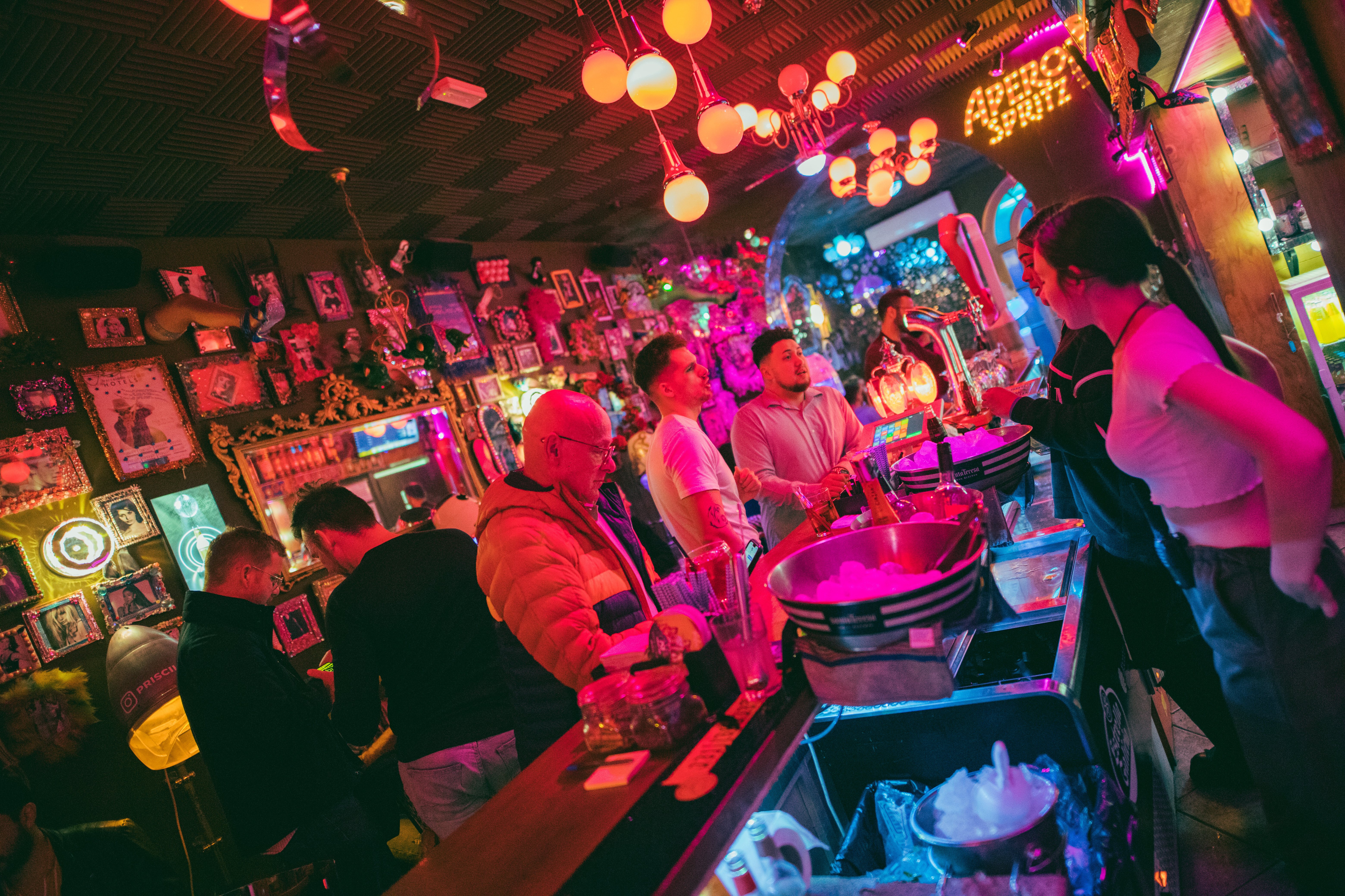 Bar Priscilla con ambiente retro y vibrante, lleno de decoraciones eclécticas y luces de neón que crean una atmósfera única y animada.
