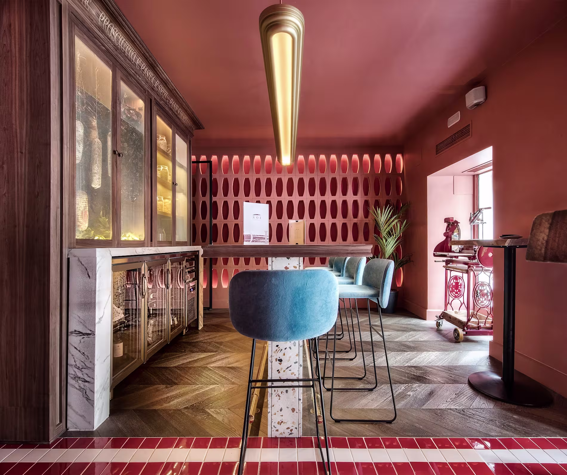 La imagen muestra una copa de cóctel con un líquido de color rosado con una capa espumosa en la parte superior. La bebida está decorada con pequeñas especias o hierbas marrones espolvoreadas encima.