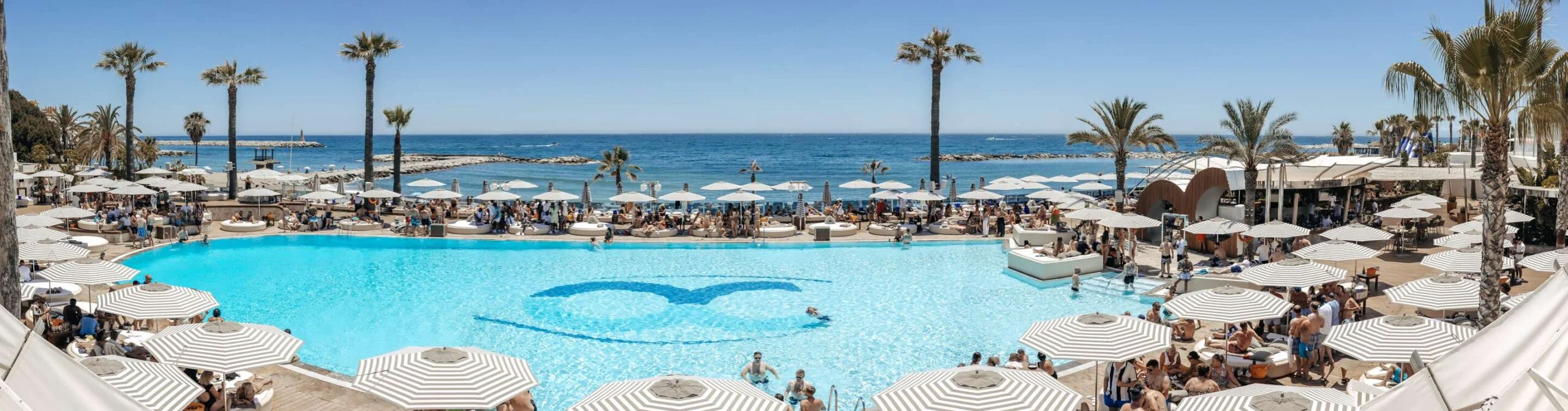 Ocean Club ofrece un paraíso junto al mar con una amplia piscina, sombrillas elegantes y un ambiente vibrante perfecto para disfrutar del lujo.