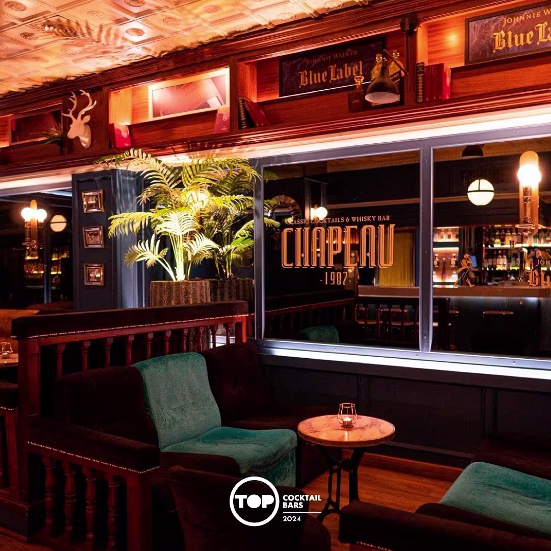 Interior de Chapeau 1987, un elegante whisky y cocktail bar, con sofás de terciopelo, iluminación cálida y detalles clásicos.