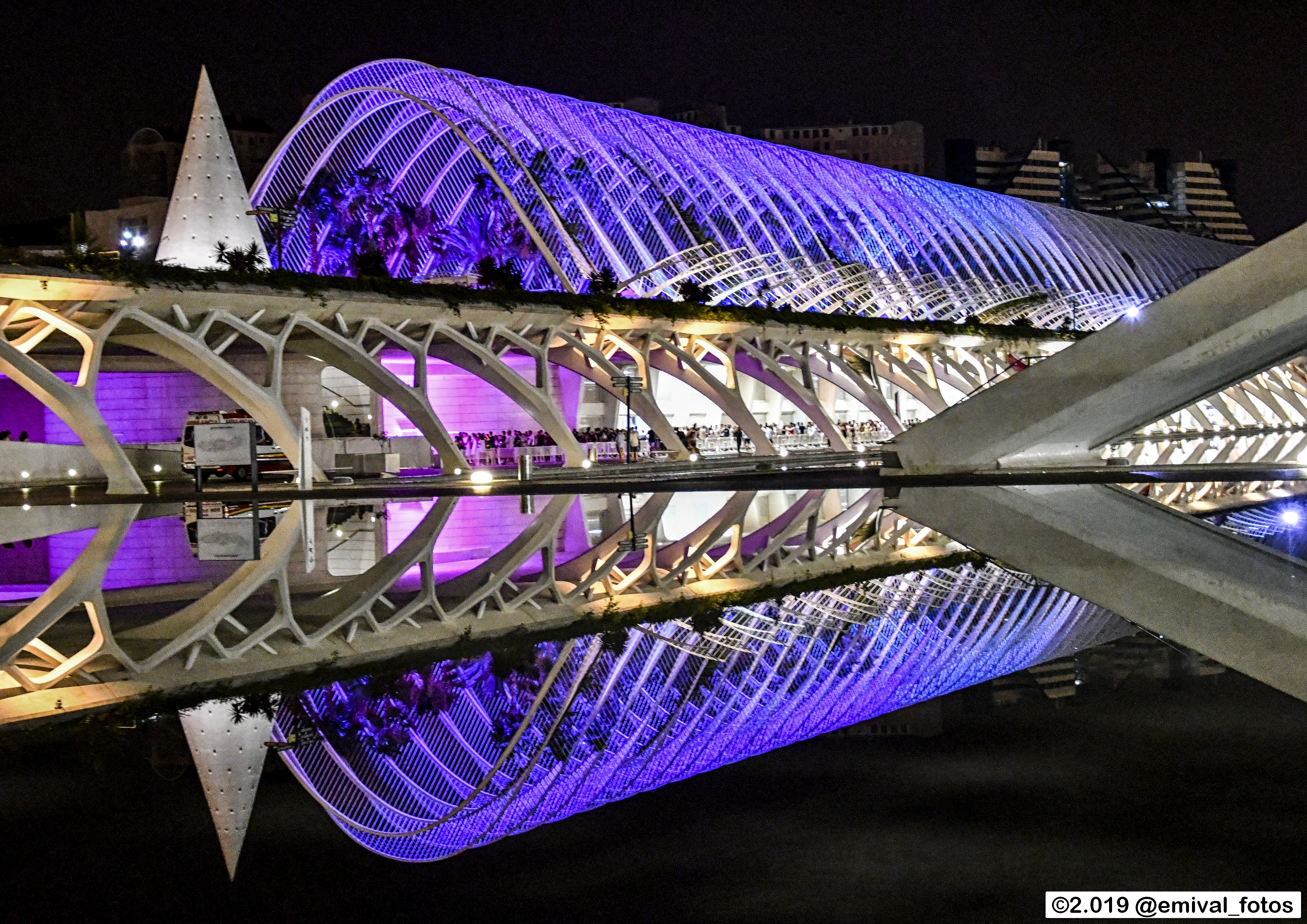 The Bar | L’Umbracle - Vista nocturna de la terraza de L’Umbracle iluminada con luces púrpuras, rodeada de palmeras y estructuras arquitectónicas modernas.