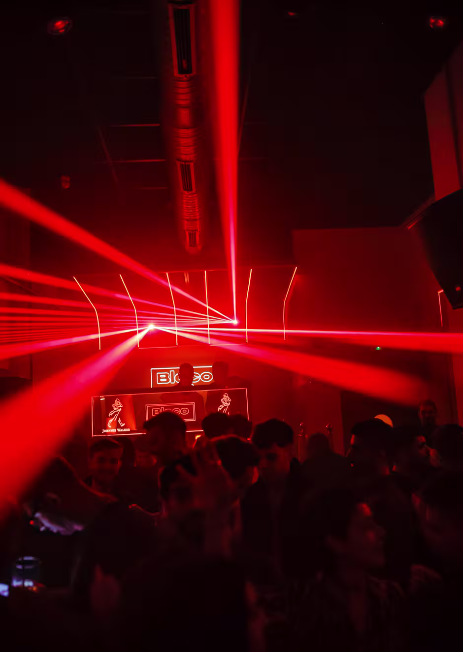 Bleco Club con luces láser rojas y cabina de DJ, creando una atmósfera vibrante y llena de energía para noches inolvidables.