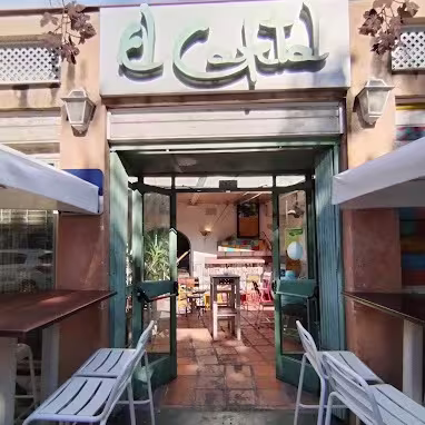 El Cafetal destaca por su entrada rústica con puertas verdes y un interior cálido lleno de mesas coloridas y decoración acogedora.