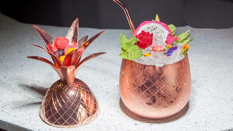 Un cóctel tropical servido en copa de piña, con flores, frutas y hielo picado. Fresco, exótico y listo para deslumbrar.