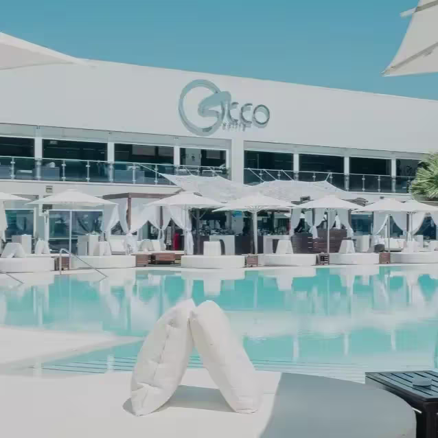 Zona de piscina con camas balinesas y sombrillas blancas en Occo, ideal para relajarse bajo el sol con todo el estilo.