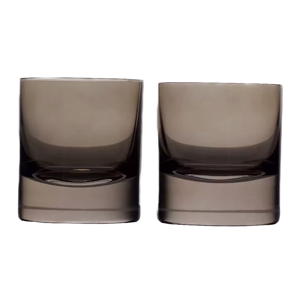 Two short, wide, transparent drinking glasses with a slightly tinted hue, placed side by side against a black background.
