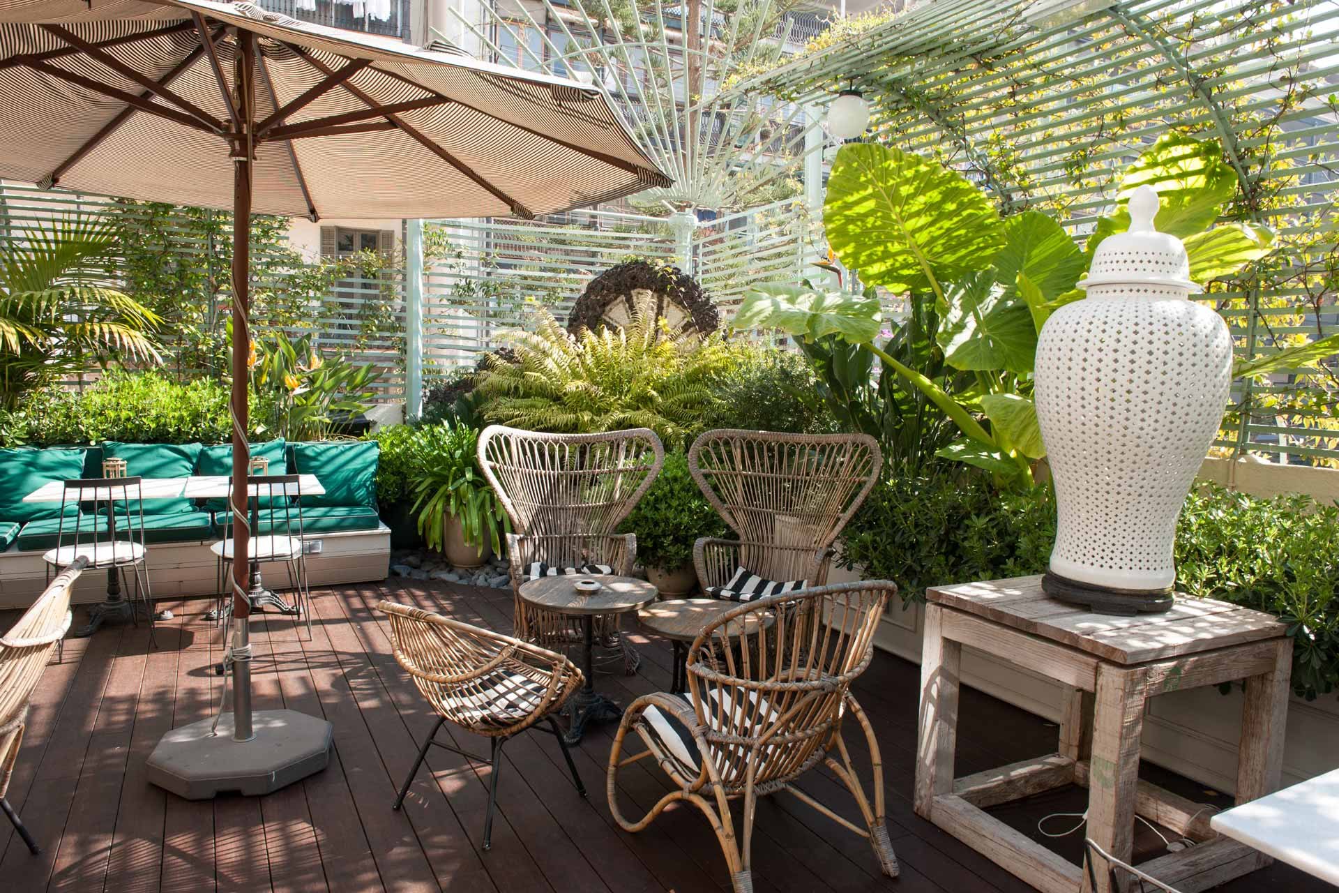El Cotton House ofrece una terraza rodeada de vegetación exuberante, con asientos de ratán y un diseño que transmite tranquilidad y sofisticación.