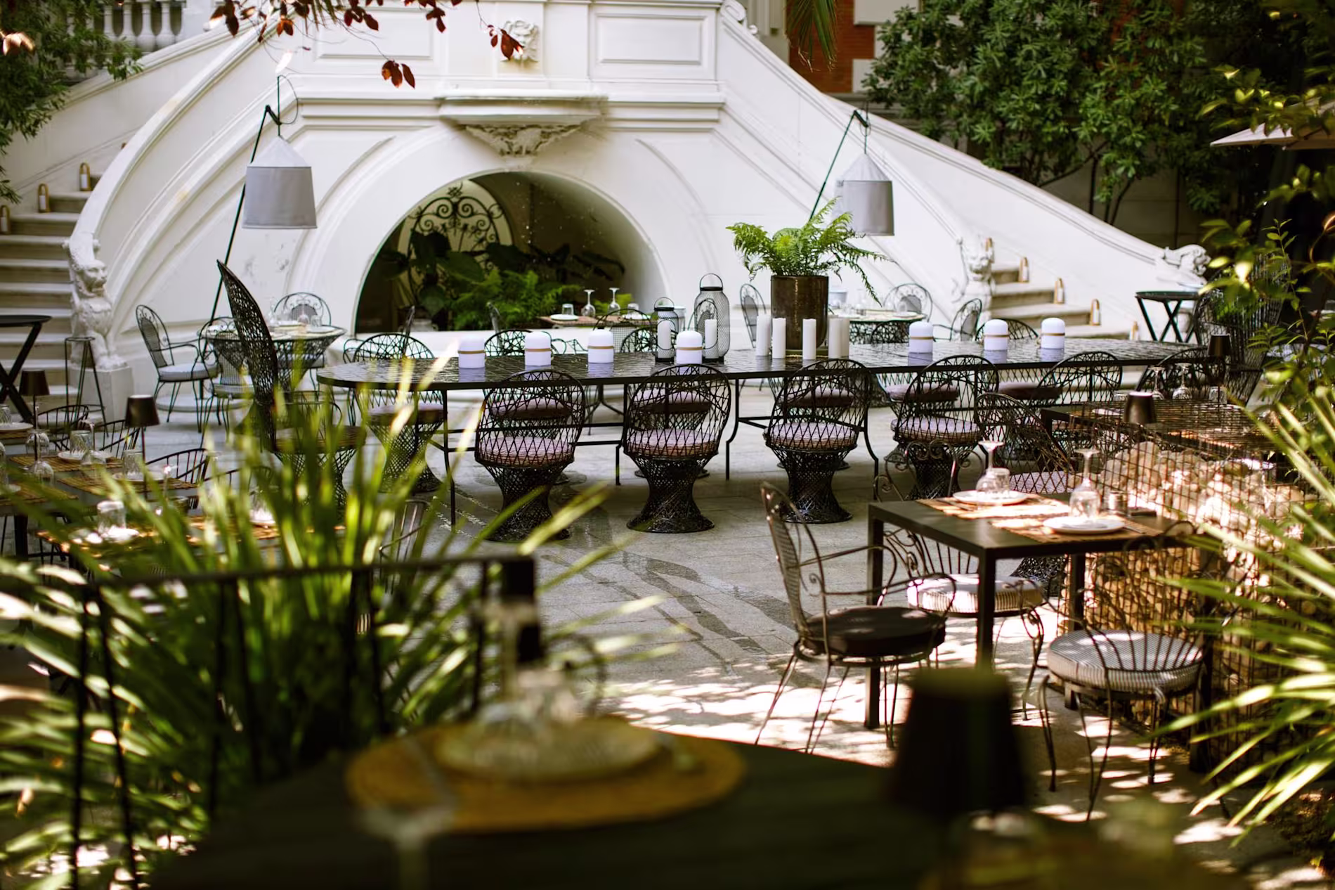 En Raimunda, un jardín encantador con muebles de hierro forjado rodea una majestuosa escalera blanca, creando un ambiente único y acogedor.