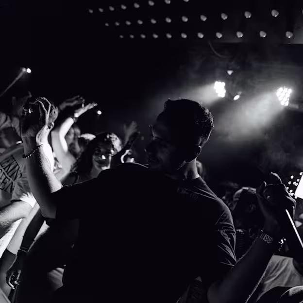 Ambiente vibrante en Bottom Club con un público disfrutando de la música en una atmósfera oscura e íntima, iluminada por focos intensos.