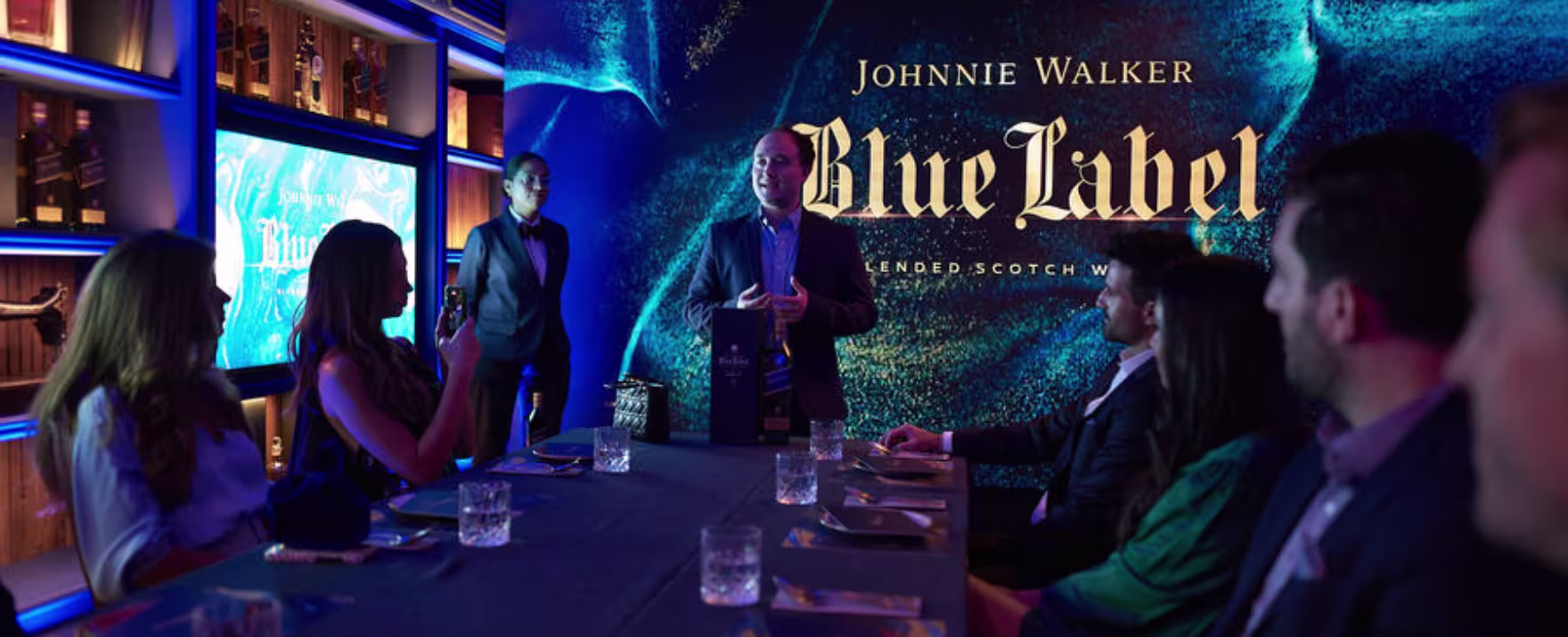 Mesa de Johnnie Walker con vasos y tres personas