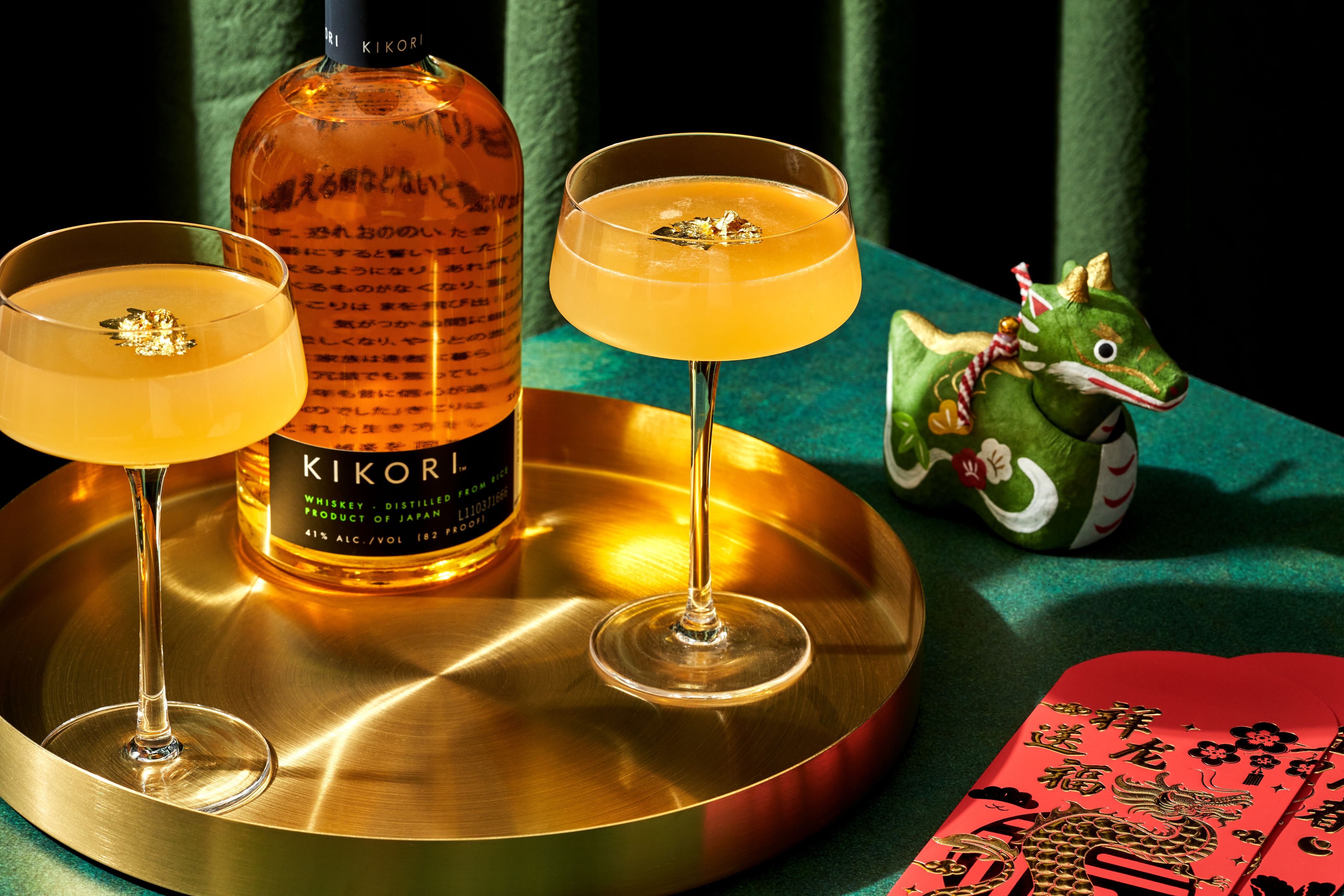 Two Kikori Whiskey cocktails on a green table setting with vibrant decor.