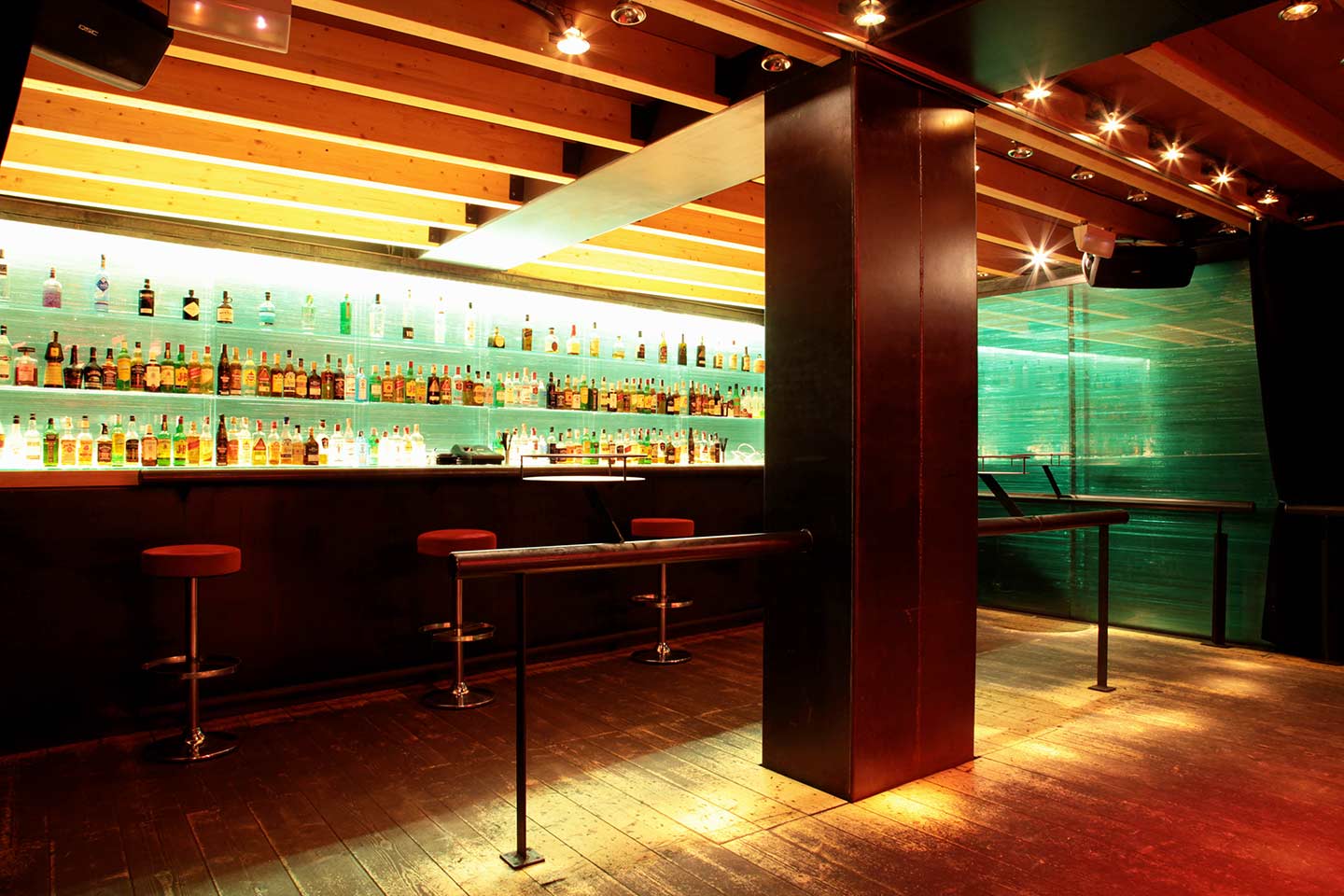 Interior de Marula Café con una barra retroiluminada, estantes llenos de botellas y un diseño moderno con techos de madera y suelos oscuros.