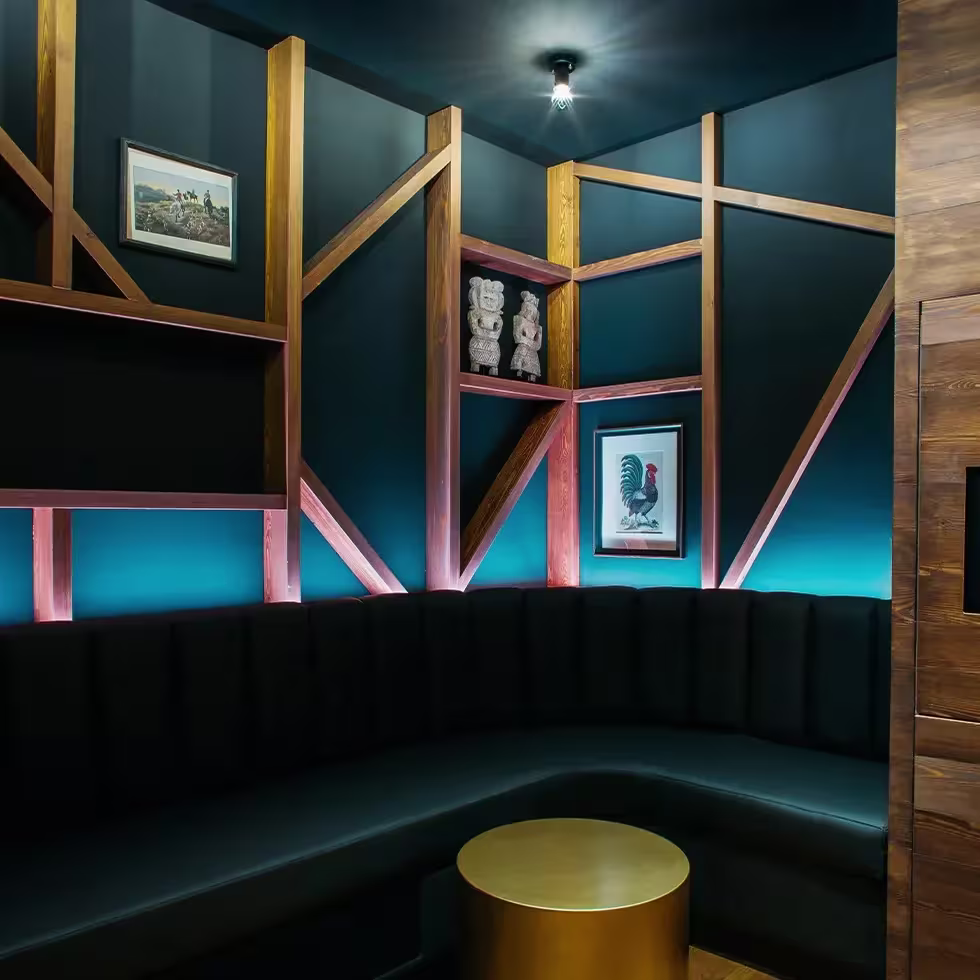 Un salón privado en BAM Karaoke Recoletos con un diseño elegante de tonos oscuros, sofás acolchados, decoraciones artísticas y luz ambiental.