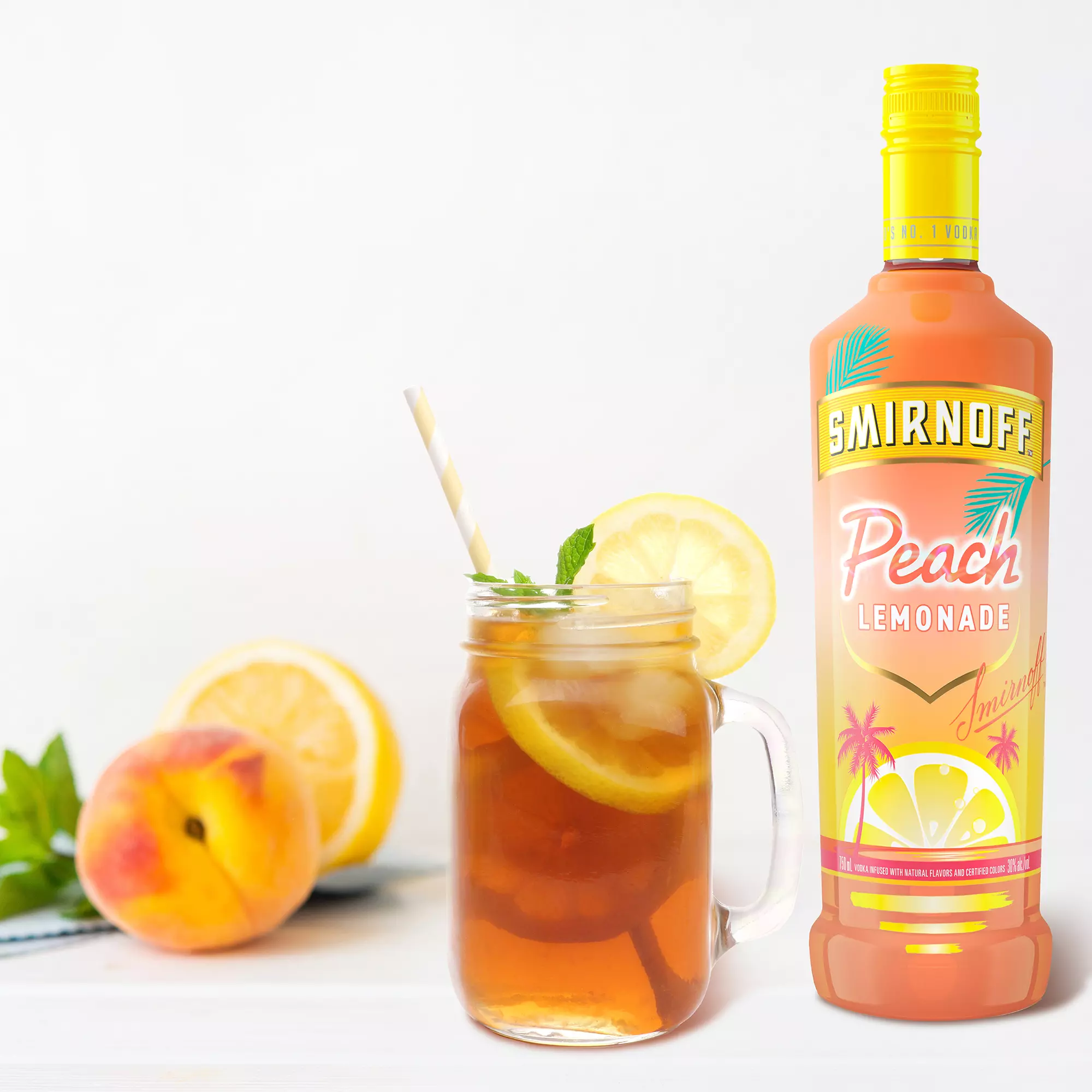 A bottle of Smirnoff Peach Lemonade stands next to a mason jar filled with iced tea, lemon slices, a peach, and a striped straw on a white surface.