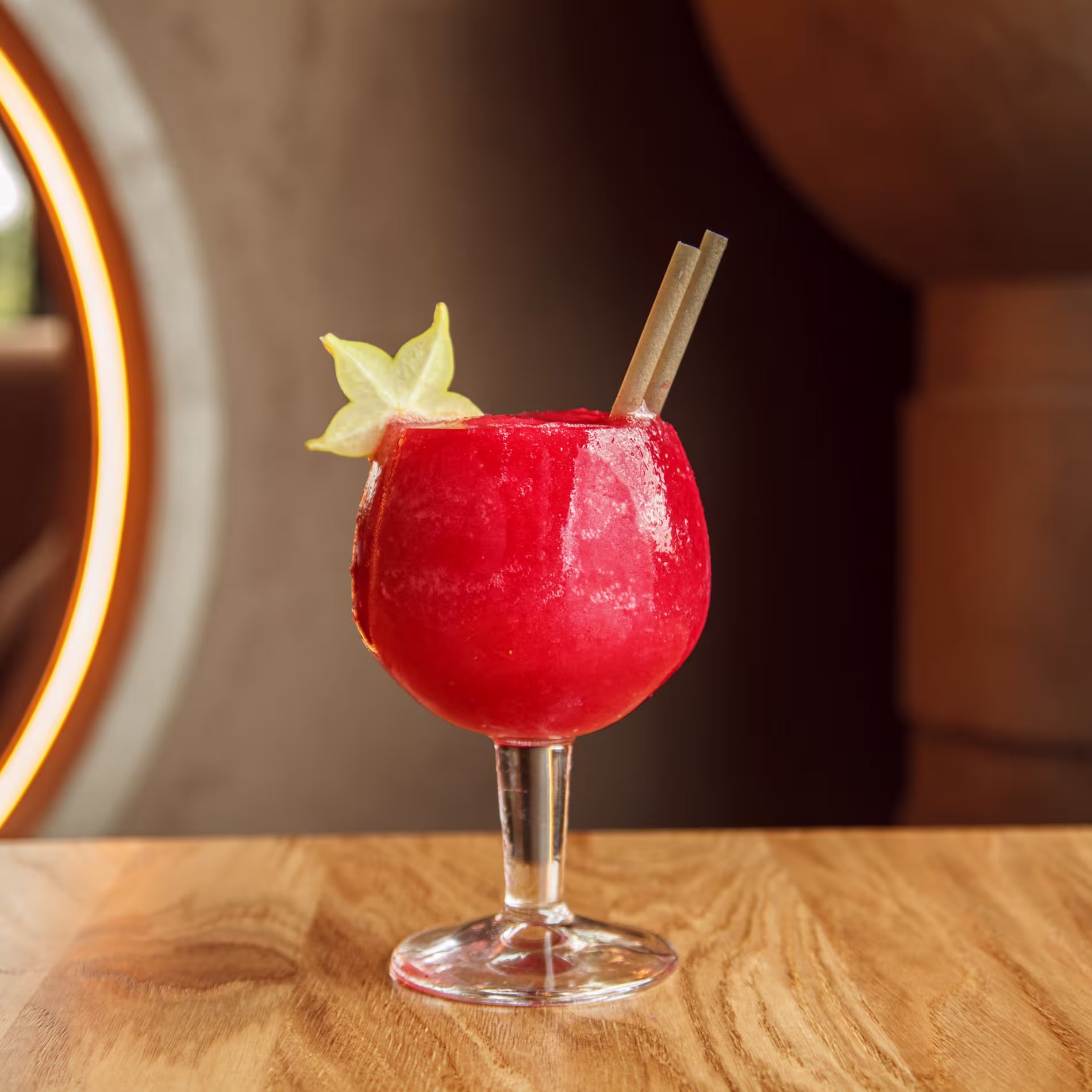 Cóctel granizado rojo servido en copa de balón en Ochenta Grados Las Tablas, con fruta en forma de estrella y fondo cálido y elegante.