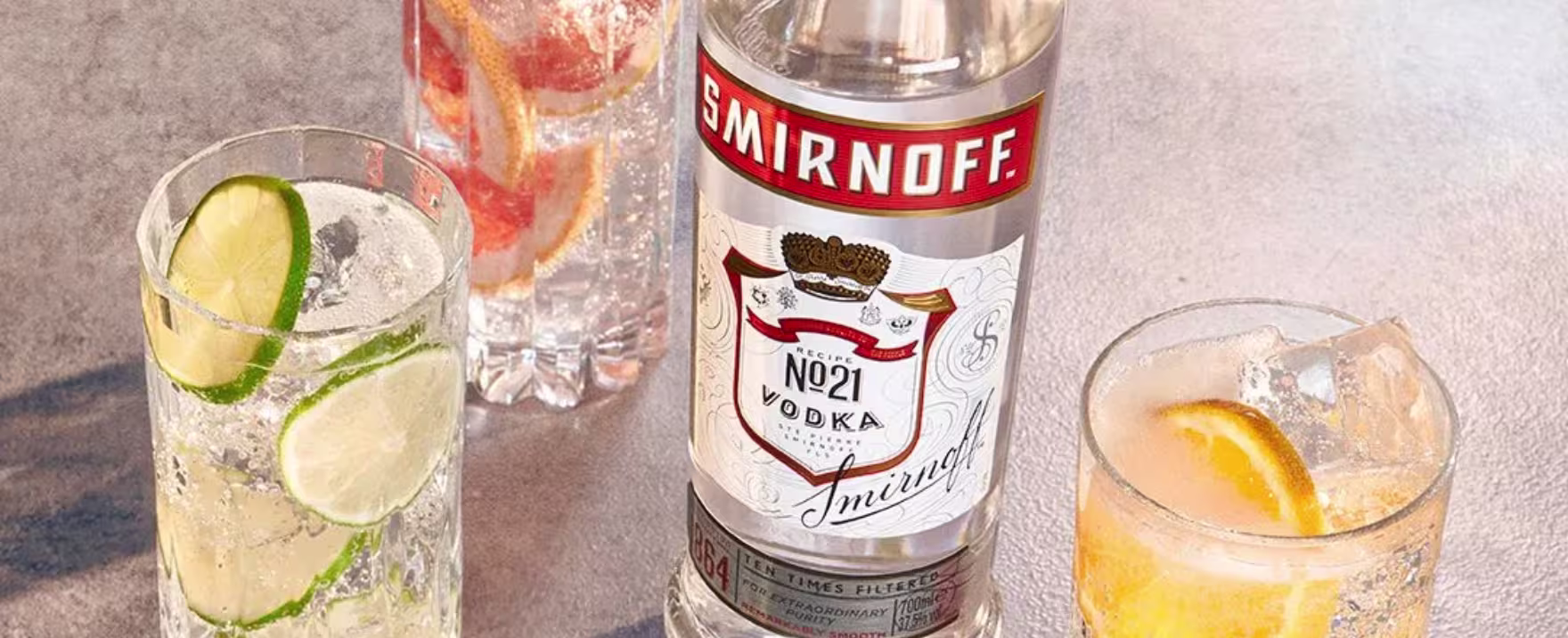 La imagen muestra una botella de Sminroff n°21 con tres vasos rellenos con cócteles preparados con dicho destilado.