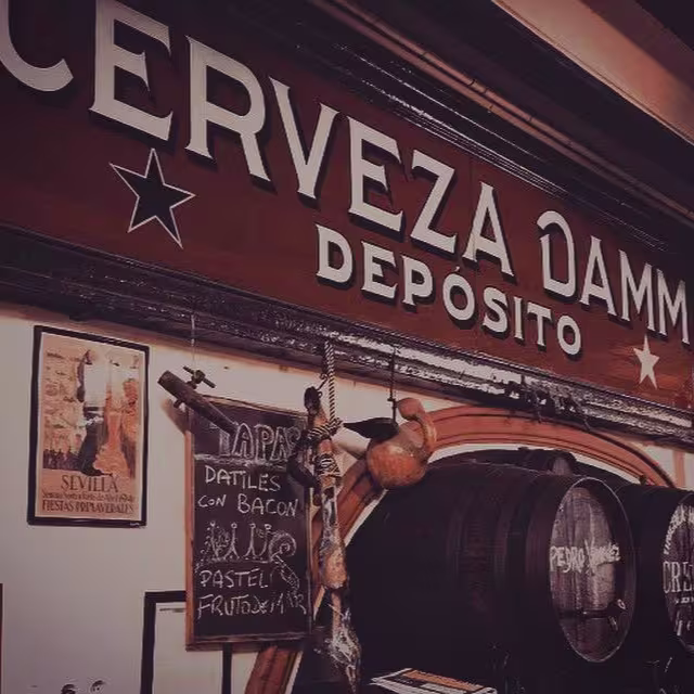 Barriles de vino, jamón colgado y cartel de tapas en Bodega Díaz Salazar, donde el alma andaluza se saborea entre cañas y tradición.