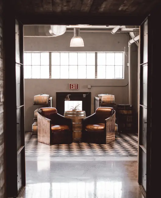 Interior of Balcones Bottle Shop and Tasting Room featuring chairs, tables, and whiskey displays.