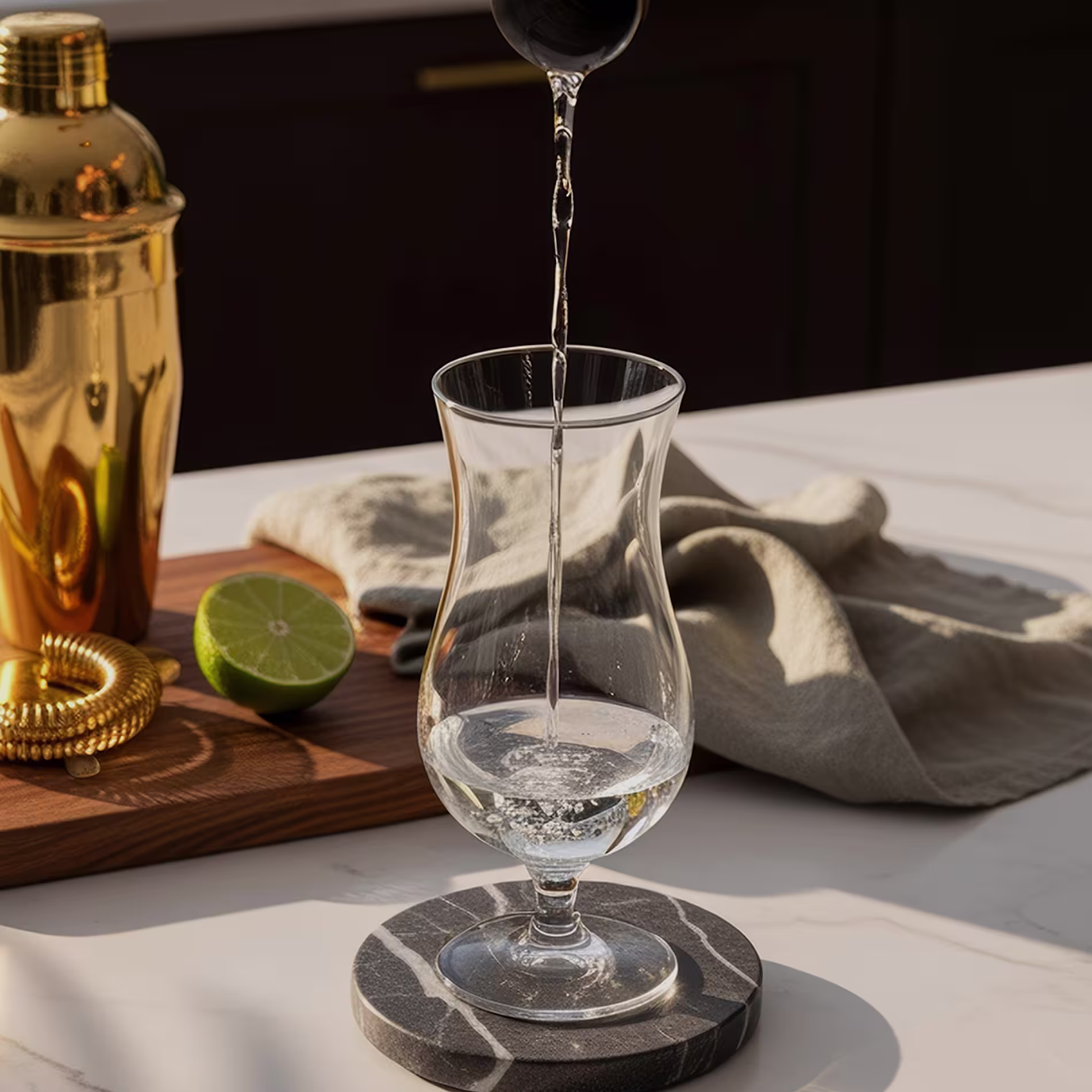 Clear liquid is poured from a jigger into a tall glass.