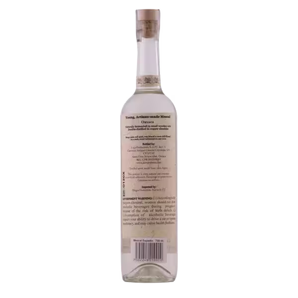 A clear glass bottle of mezcal shown from the back, displaying a beige label with product information, warnings, and a barcode.
