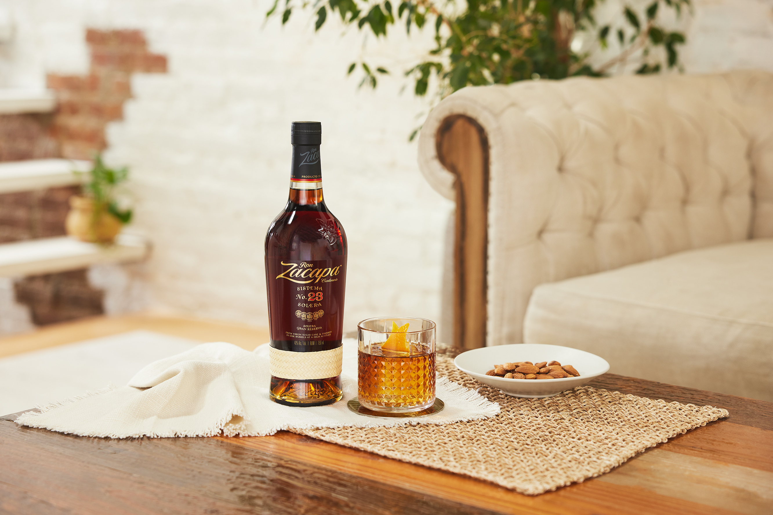 Un hombre y una mujer disfrutan de unos cócteles «Rum Old Fashioned», con una botella de ron Zacapa sobre la mesa