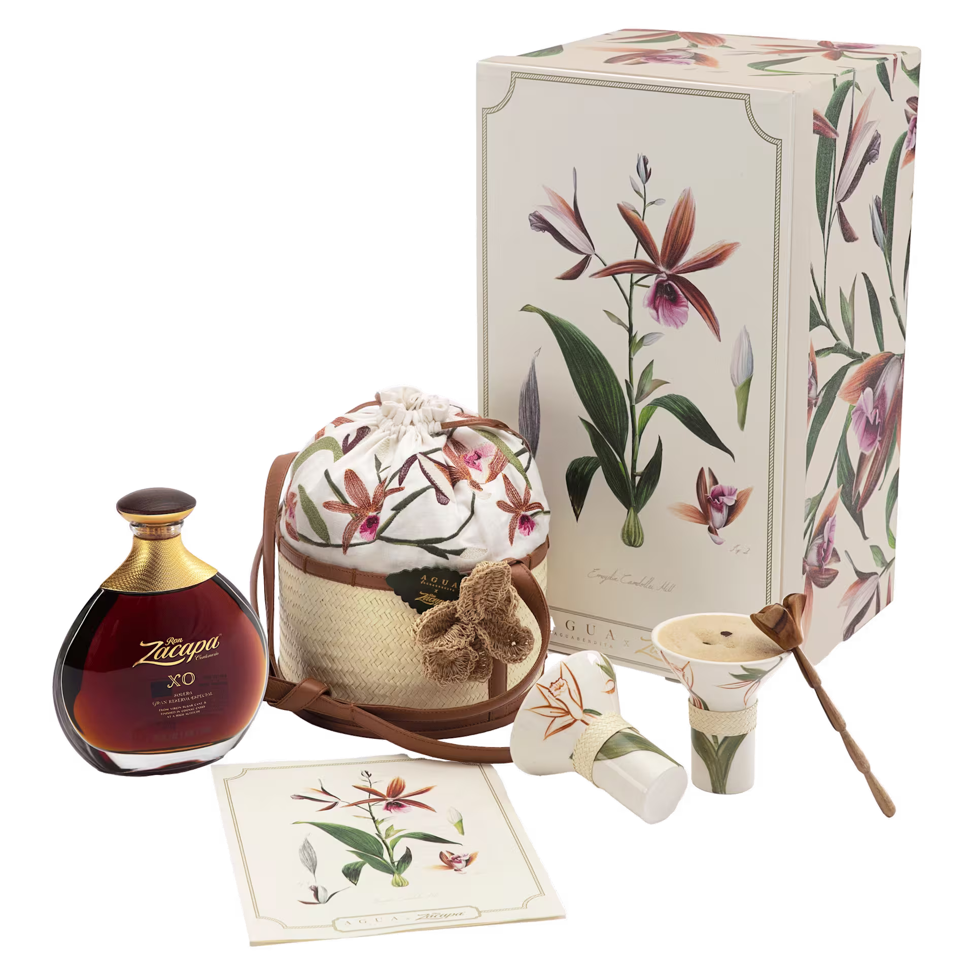 A gift set with a floral box, a bottle of Ron Zacapa XO rum, a printed drawstring bag, a postcard, and two ceramic cups with a wooden stirrer and lid.