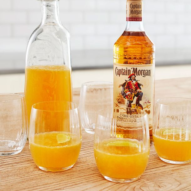 Cocktail Captain Morgan Original Rum & Orange garnisit cu portocale așezat pe un șervețel cu dungi albastre și albe