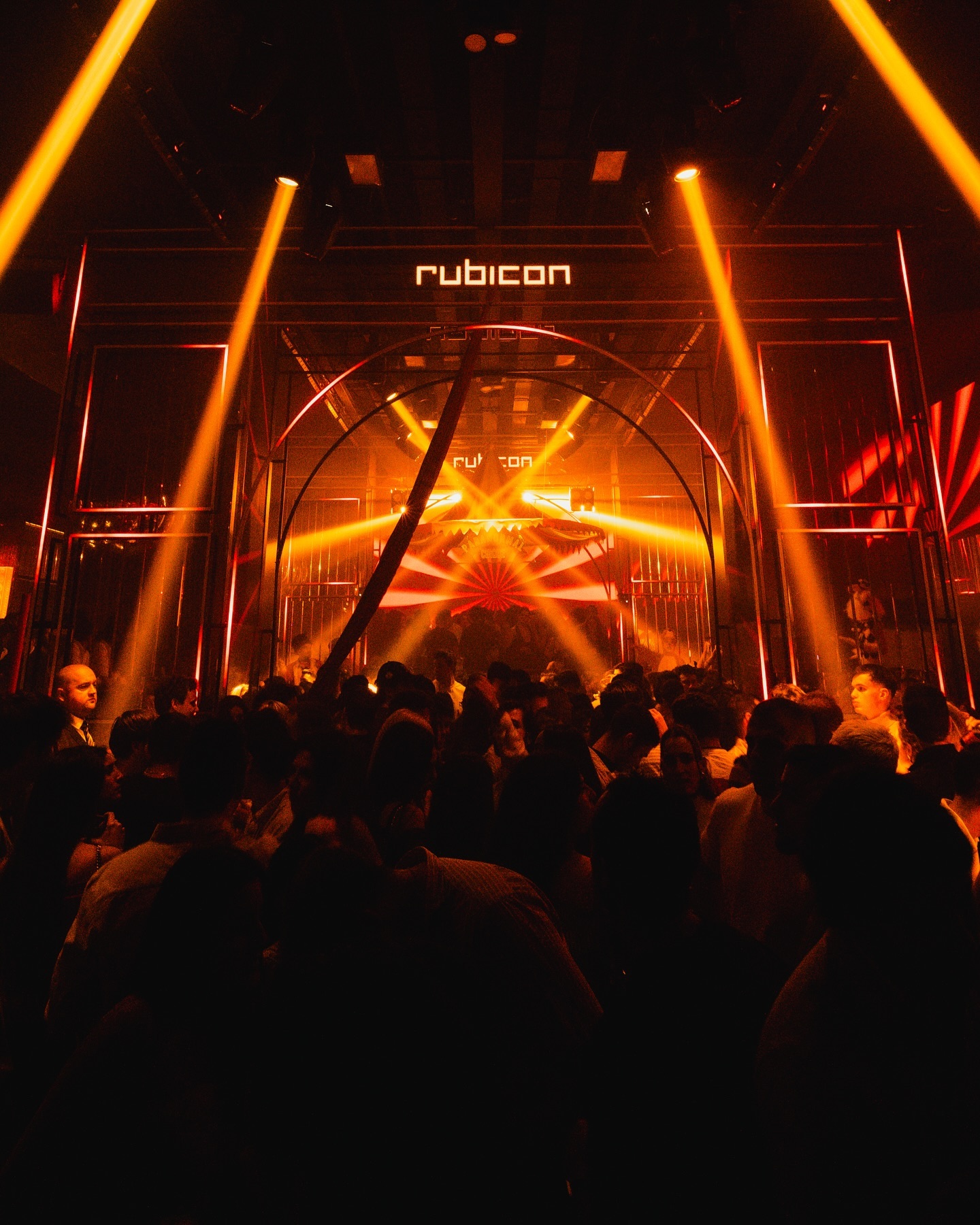 Ambiente exclusivo en Rubicon con luces cálidas, diseño arquitectónico moderno y una multitud disfrutando de la noche.