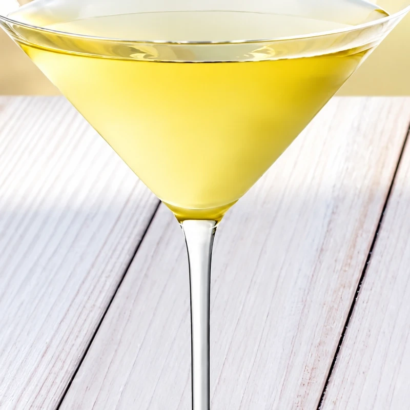 Cóctel appletini servido en copa de martini sobre una mesa de madera clara