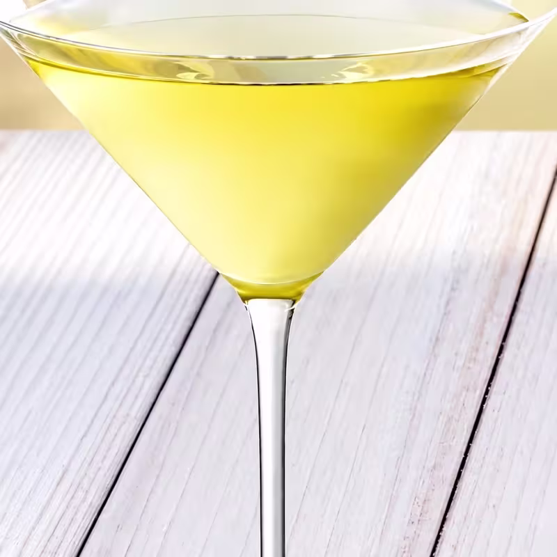 Cóctel appletini servido en copa de martini sobre una mesa de madera clara