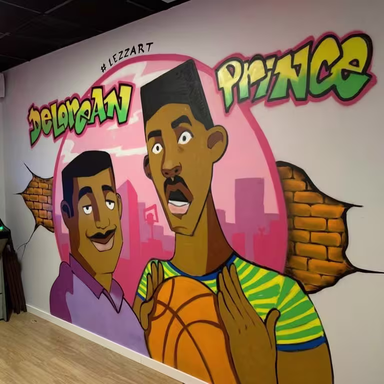Mural de estilo noventero en Delorean Lounge Ruzafa con homenaje a "El Príncipe de Bel-Air" y máquina arcade retro en la esquina.