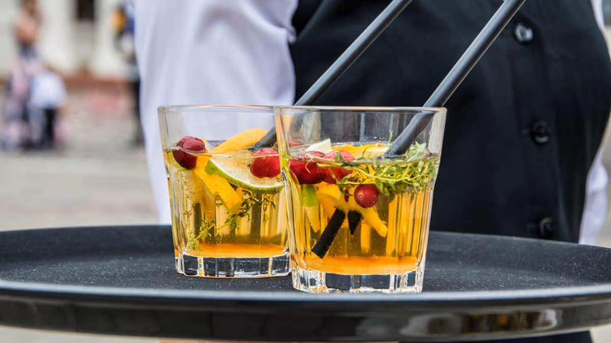 Two orange cocktails on a tray using kitchen scraps as garnishes