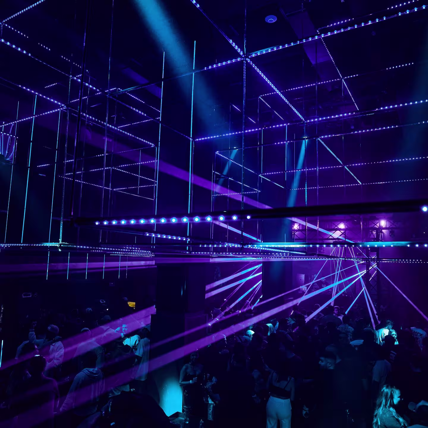 Ambiente vibrante en Art Club, con una multitud disfrutando bajo luces de neón y un escenario iluminado en una sala de diseño moderno.