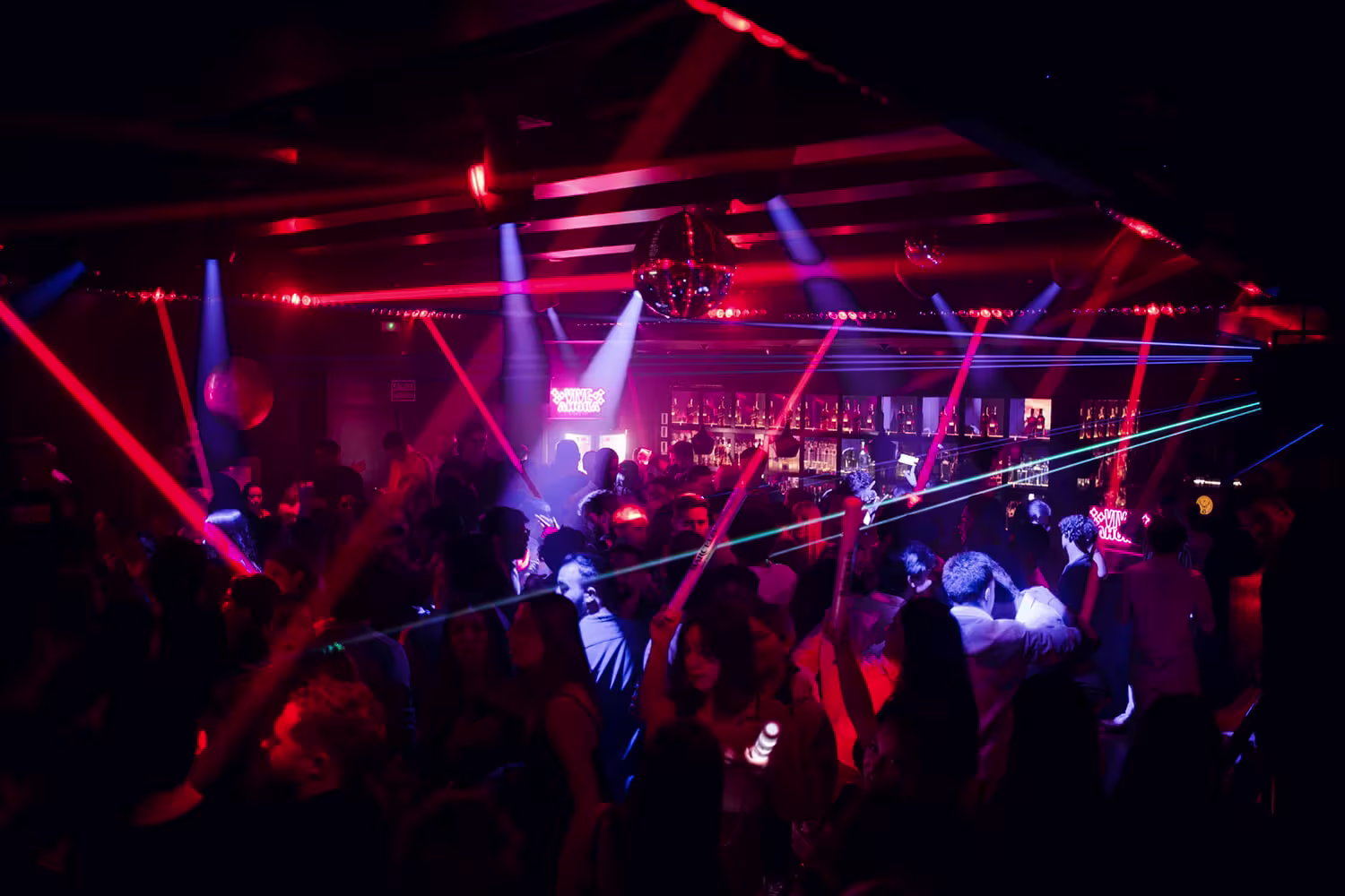 Uthopia con luces láser rojas y azules, pista de baile repleta y ambiente vibrante para noches de fiesta inolvidables.