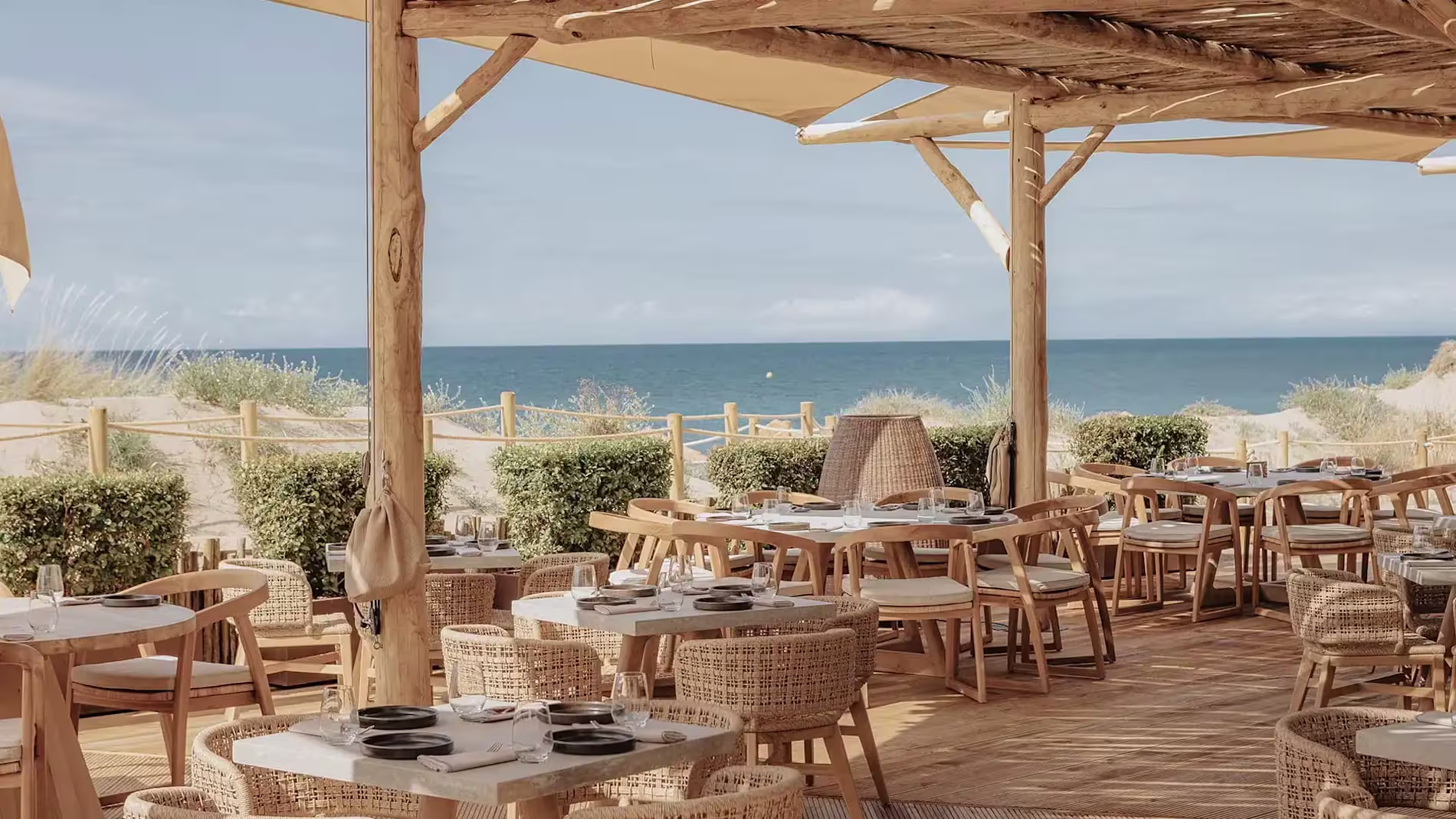 El ambiente relajado de Dune Beach, con mesas de madera y vistas al mar, ofrece una experiencia única junto a la playa.