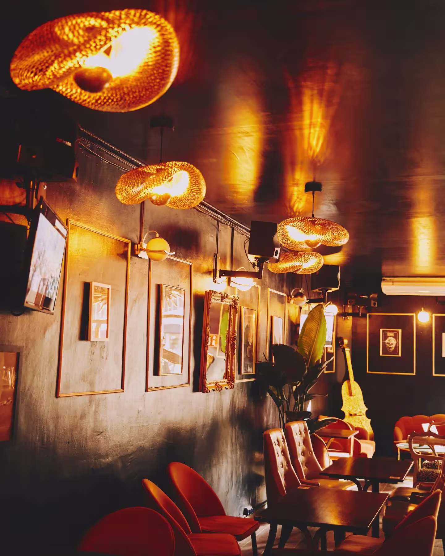 Espacio cálido con iluminación dorada, paredes oscuras, muebles vintage y detalles retro que crean una atmósfera acogedora y nostálgica.