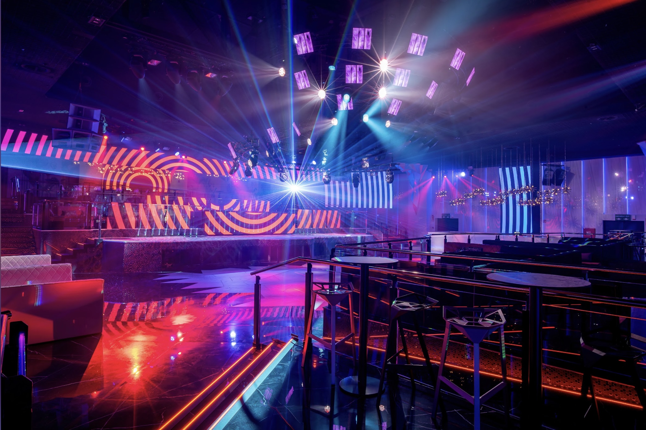 Interior de BCM, con una amplia pista de baile, luces de neón vibrantes, pantallas LED y un ambiente moderno y energético.