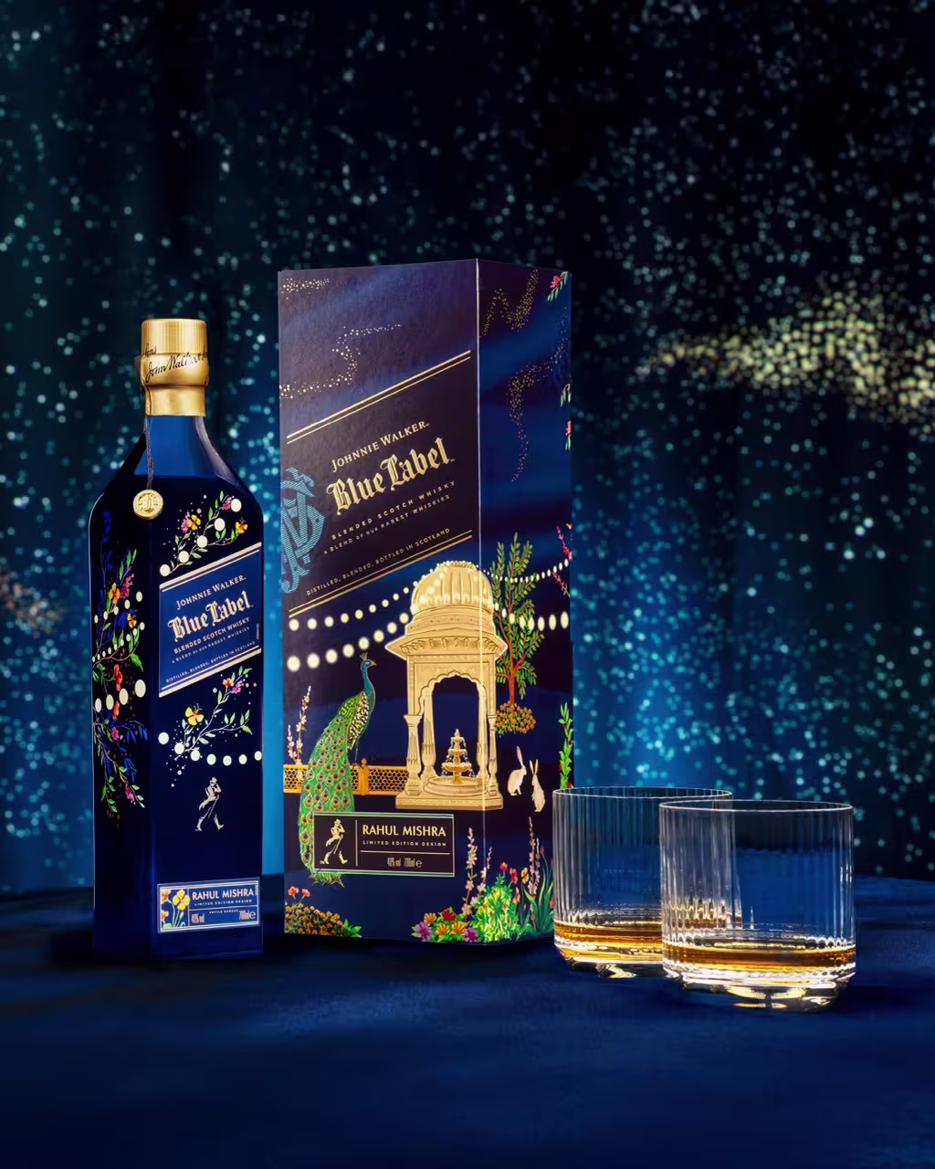 A bottle of Johnnie Walker Blue Label with a decorative box and two whiskey glasses, set against a blue, starry background.