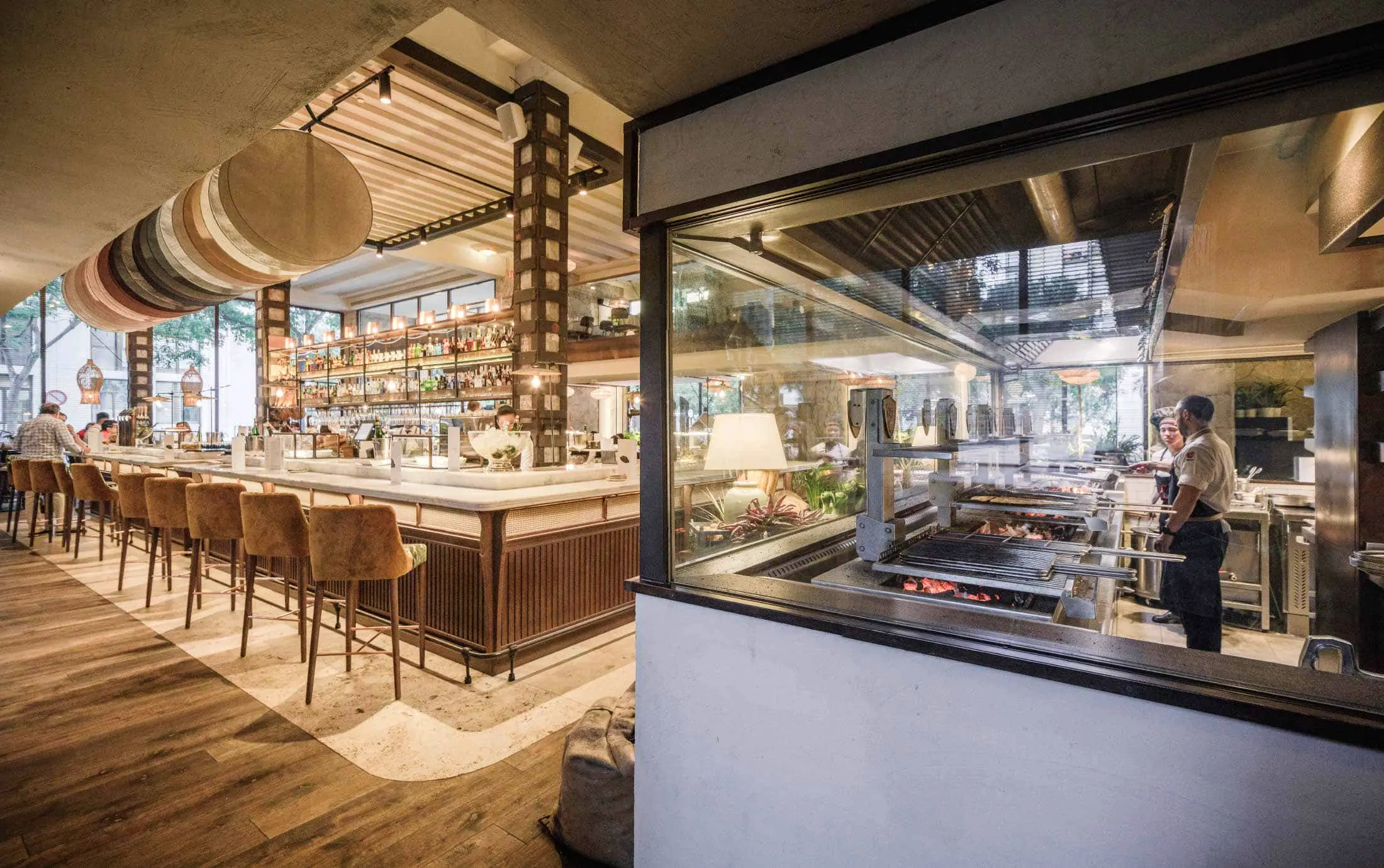 Carbón destaca su ambiente sofisticado con una barra central elegante y una cocina abierta donde los chefs preparan platos al carbón.