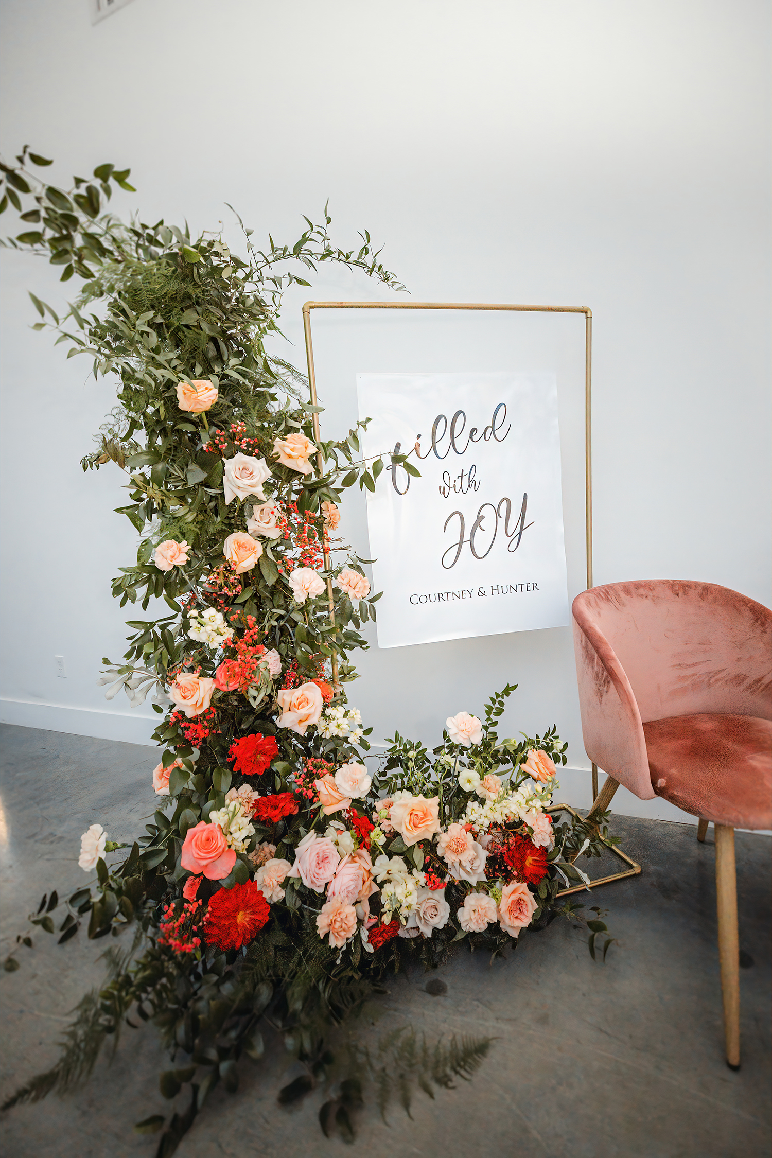 Cascading coral and red floral installation beside a welcome sign