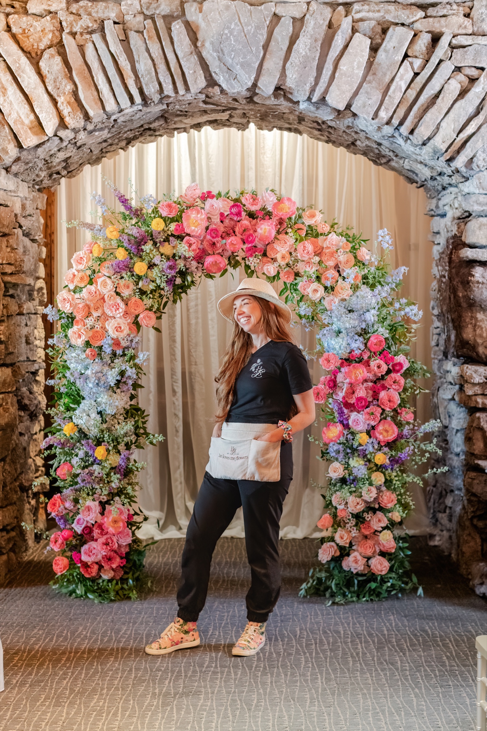 Charity of He Loves Me Flowers beside a colorful floral arch inside a stone archway at Big Cedar Lodge