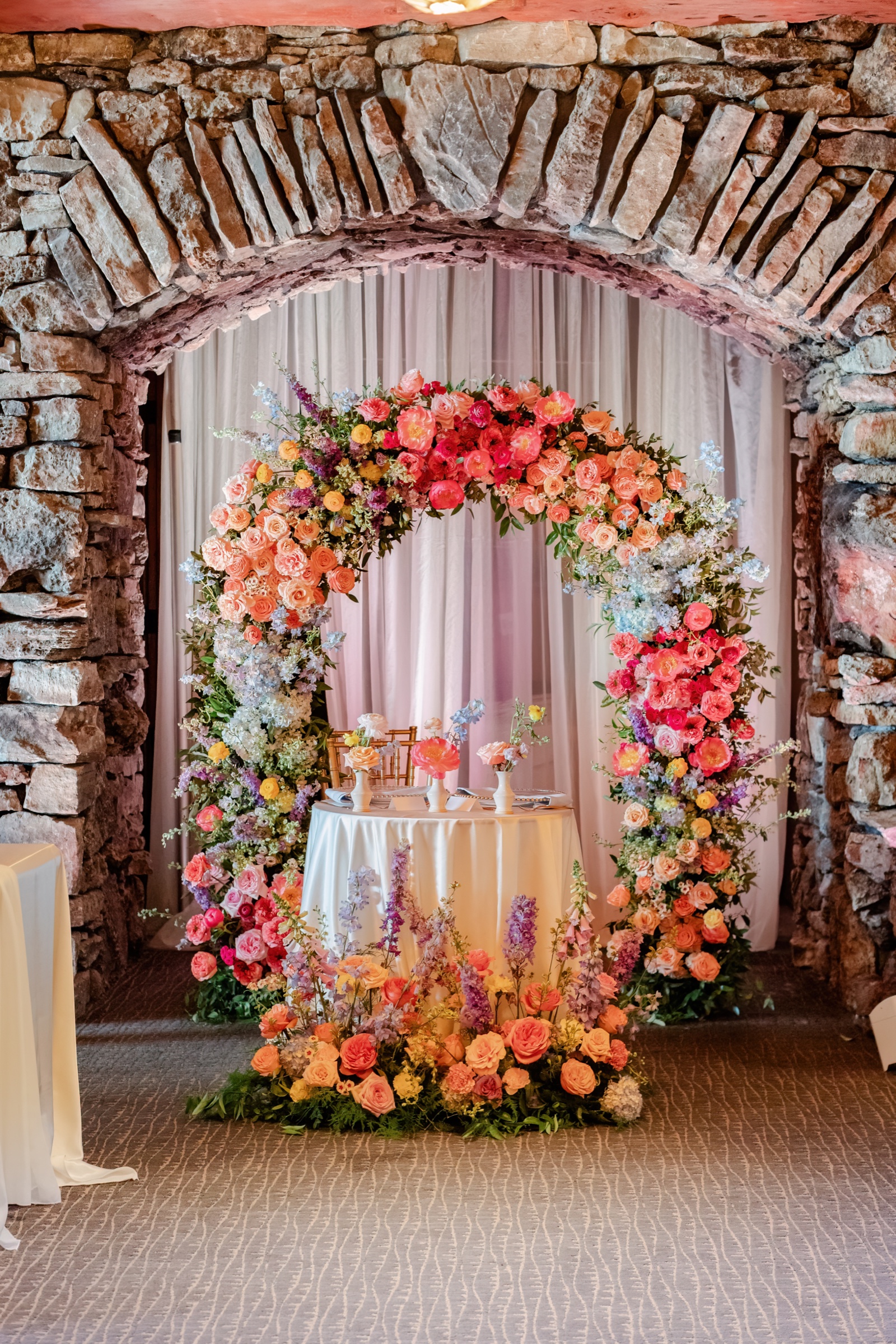 Colorful wedding ceremony floral arch by He Loves Me Flowers at Big Cedar Lodge