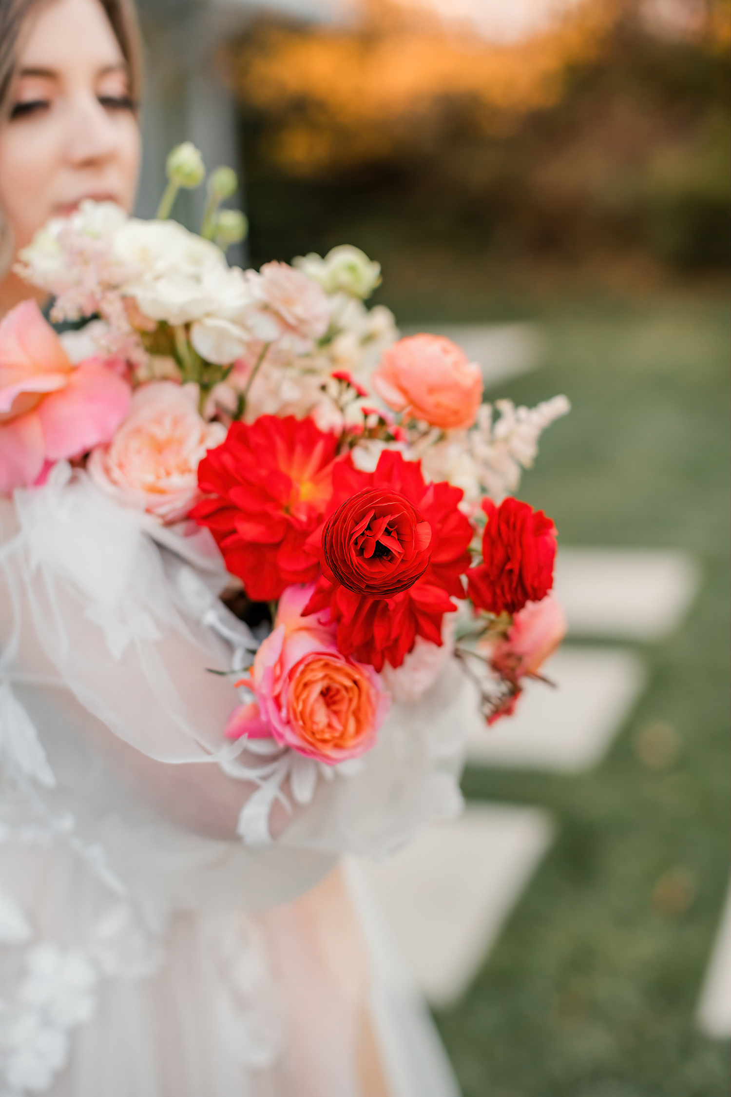 Bridal bouquet with deep red dahlias, coral ranunculus, and soft peach blooms